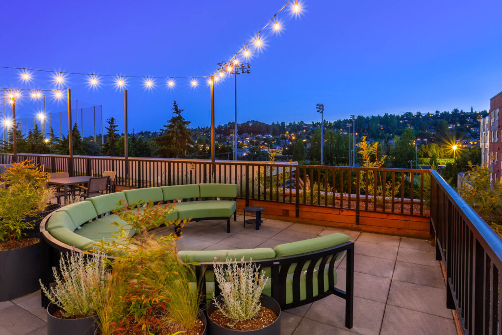 Rooftop terrace at dusk with curved bench seating and string lights at Contour Apartments